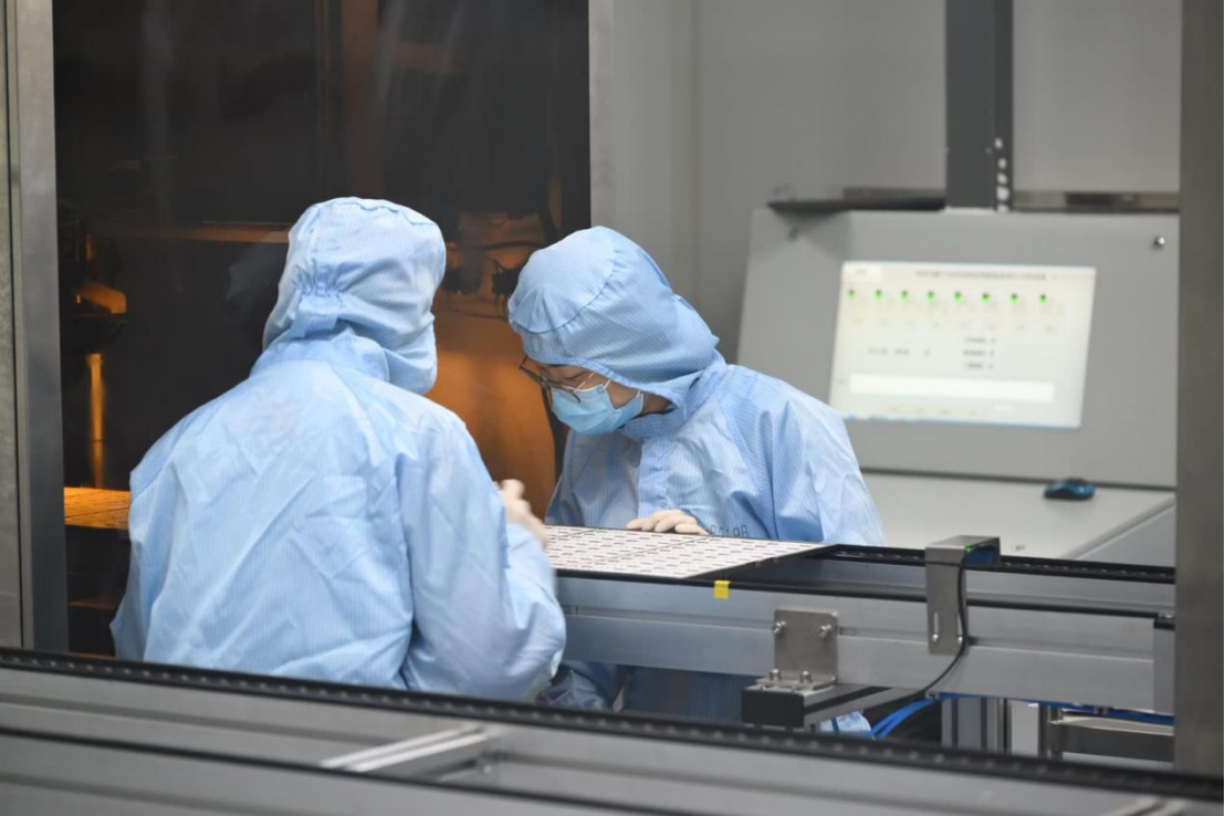 Laboratory personnel wearing protective clothing working with automated diagnostic manufacturing equipment